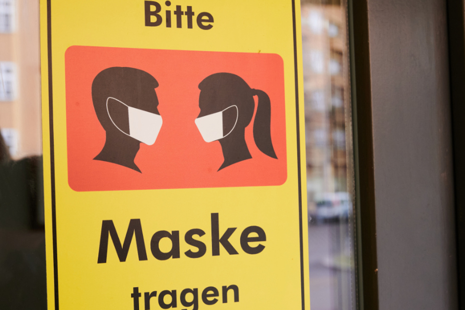 Auf einem Gebäude steht "Bitte Maske tragen". In Görlitz hat eine Frau die Maskenpflicht missachtet.