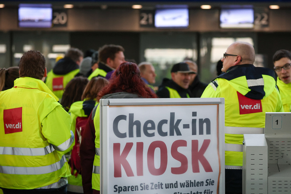 Beschäftigte der Mitteldeutschen Flughafen AG gehen während eines Warnstreiks durch den Flughafen Leipzig/Halle.