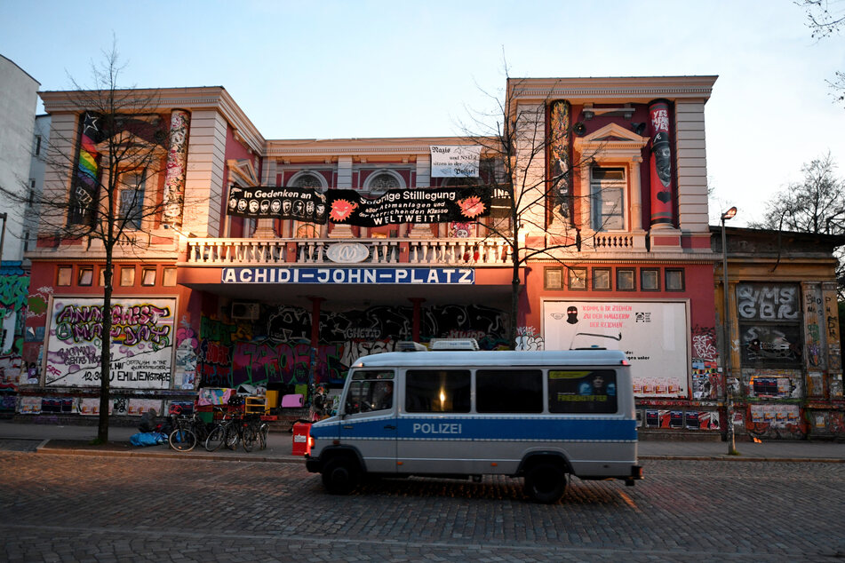 Ein Polizeiwagen steht vor dem linksautonomen Zentrum "Rote Flora" im Schanzenviertel. "Achidi-John-Platz" steht dort in dicken Lettern an der Fassade.