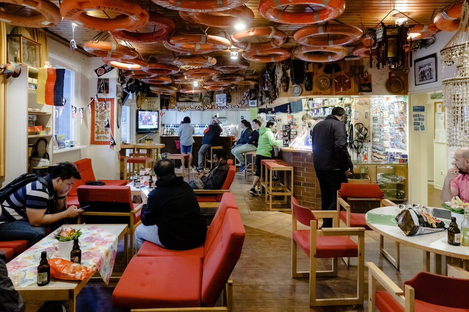 Besucher des Seemannsclubs "Duckdalben" sitzen im Multifunktionsraum mit Bar, Kantine und Einkaufsladen.