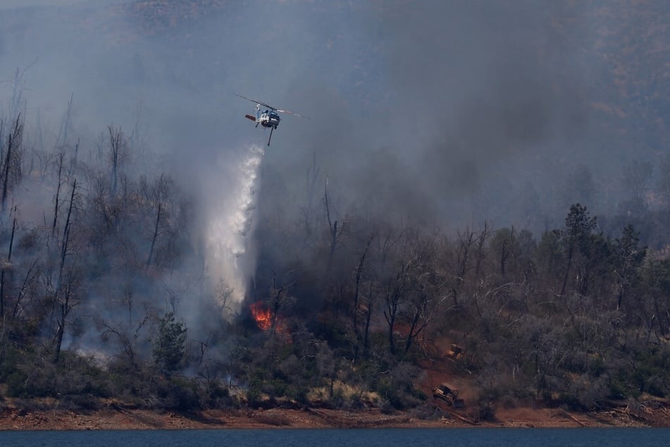 A firefighting helicopter drops water on the Thompson Fire in Oroville, California.