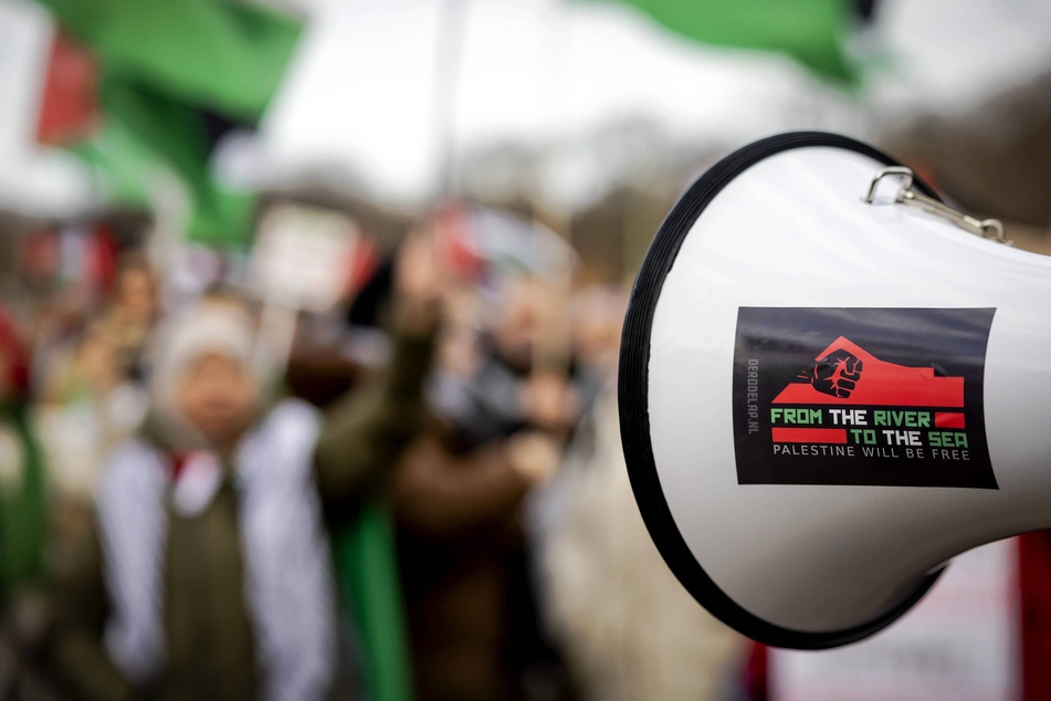 Demonstrators speak into a megaphone with a sticker reading "From the River to the Sea, Palestine Will Be Free" during a rally in The Hague, Netherlands, home of the International Court of Justice.