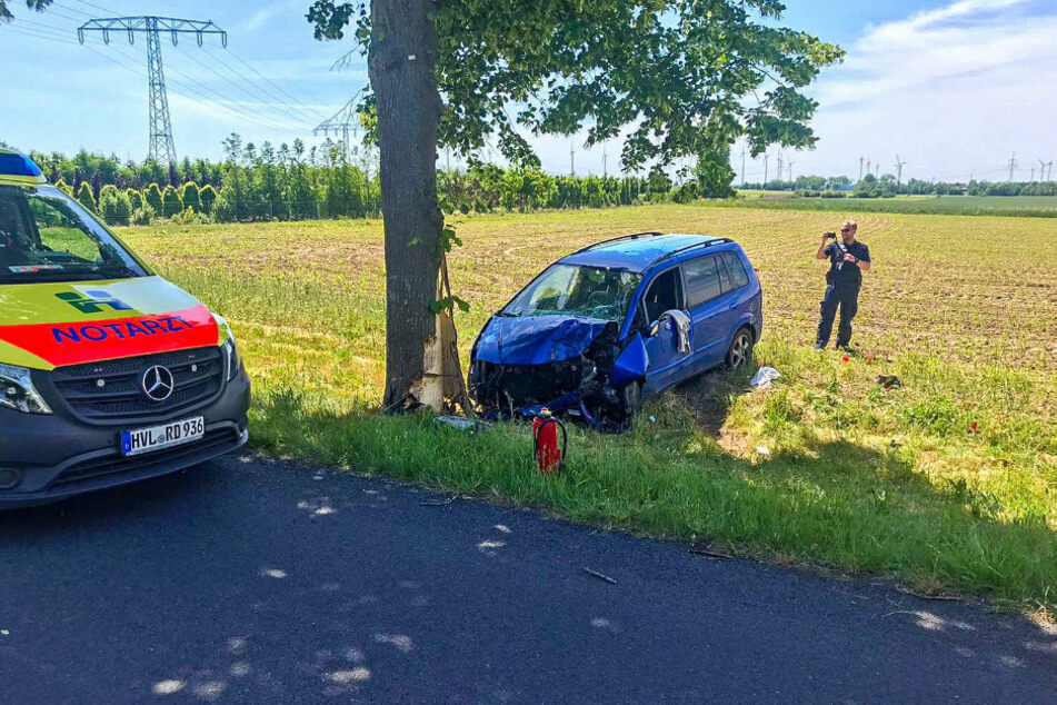 Ein Notarztfahrzeug steht auf der Straße vor dem Unfallauto.