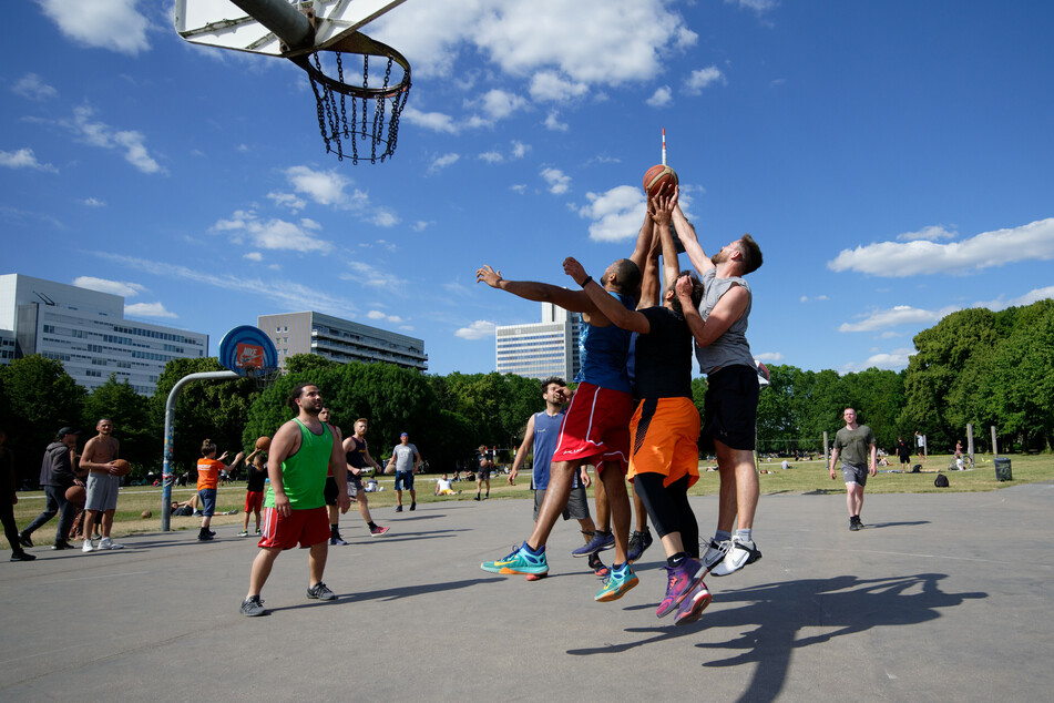 Eine Gruppe Männer spielt in einem Park Streetball.