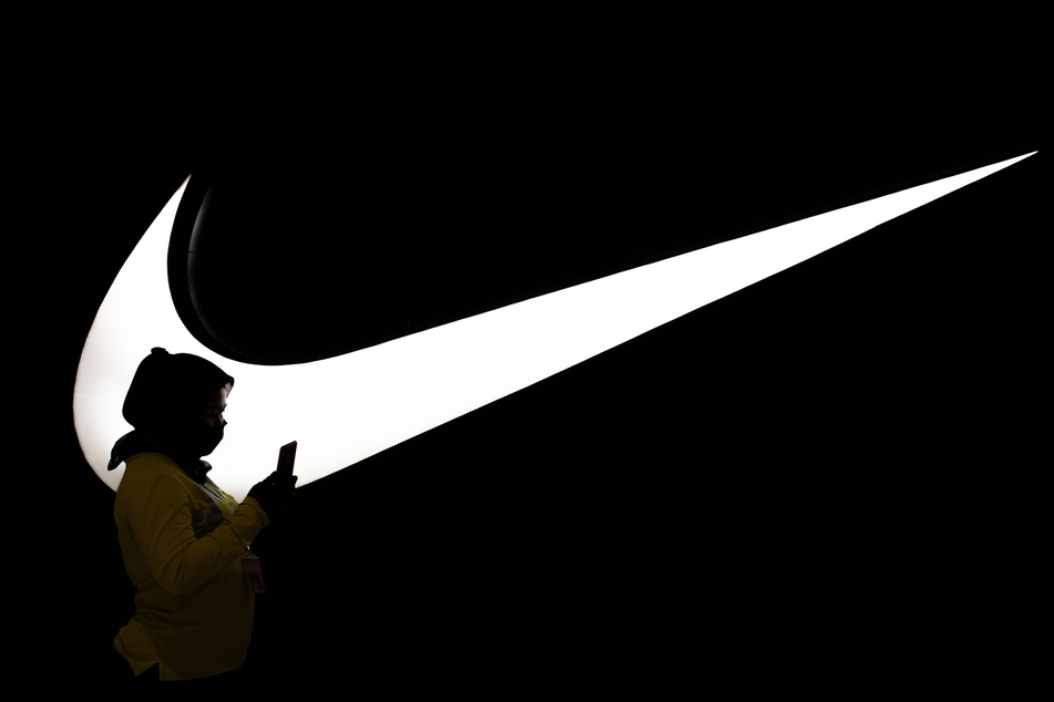 Eine Frau geht am Logo der Marke "Nike" vorbei. Obwohl sich das Zeichen auf dem "Satan-Schuh" befindet, hat der Hersteller diese nicht autorisiert.