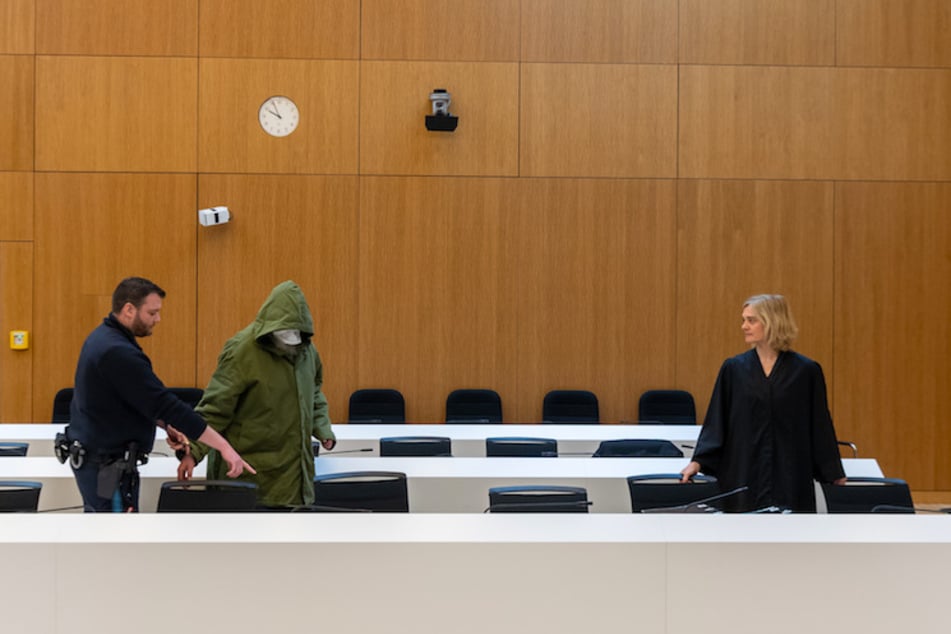 Ein 56 Jahre alter, wegen sexuellen Kindesmissbrauchs, angeklagter Mann (M) wird zu Prozessbeginn am Landgericht München II in den Saal geführt. Rechts steht seine Anwältin Anja Kollmann.