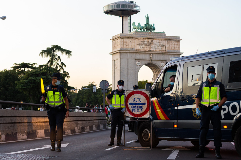 Polizisten stehen an einem Kontrollpunkt in Madrid. Die Justiz hat die umstrittene Zwangsabriegelung des Corona-Hotspots Madrid durch die spanische Zentralregierung gekippt.