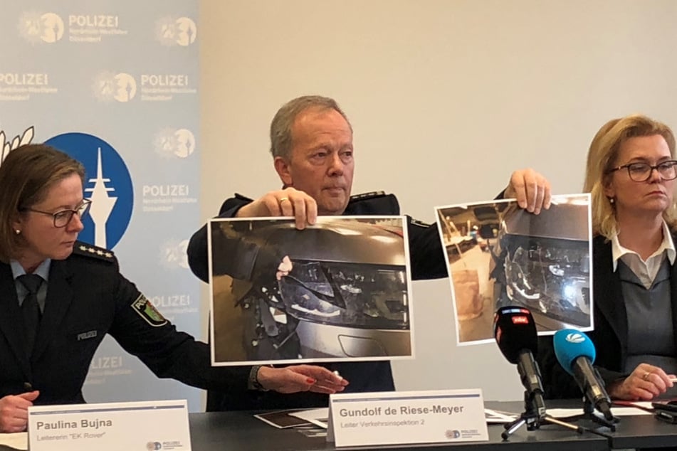 Gundolf de Riese-Meyer (Mitte), Leiter der Verkehrsinspektion, zeigt zwei Fotos des beschädigten Autos auf einer Pressekonferenz von Polizei und Staatsanwaltschaft.