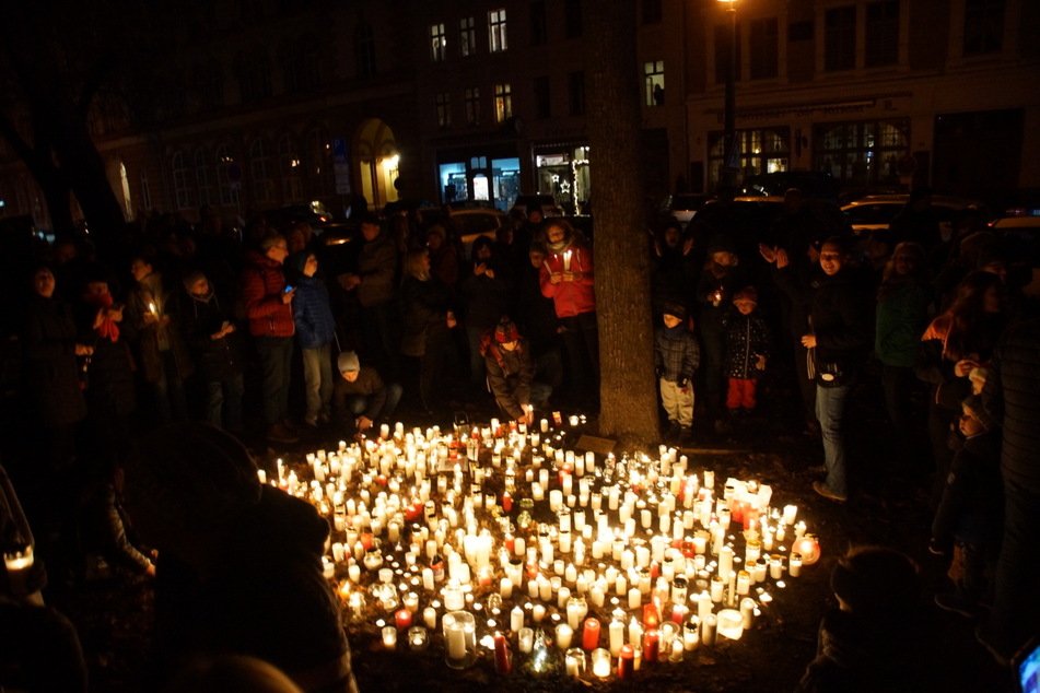 Zahlreiche Kerzen stehen nebeneinander auf dem Elisabethplatz. Ringsherum Schaulustige.