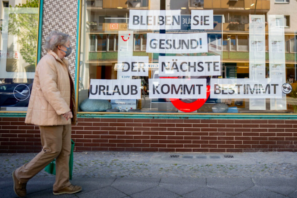 Eine Passantin mit Mund-Nasenschutz geht an einem Reisebüro vorbei. (Symbolbild)