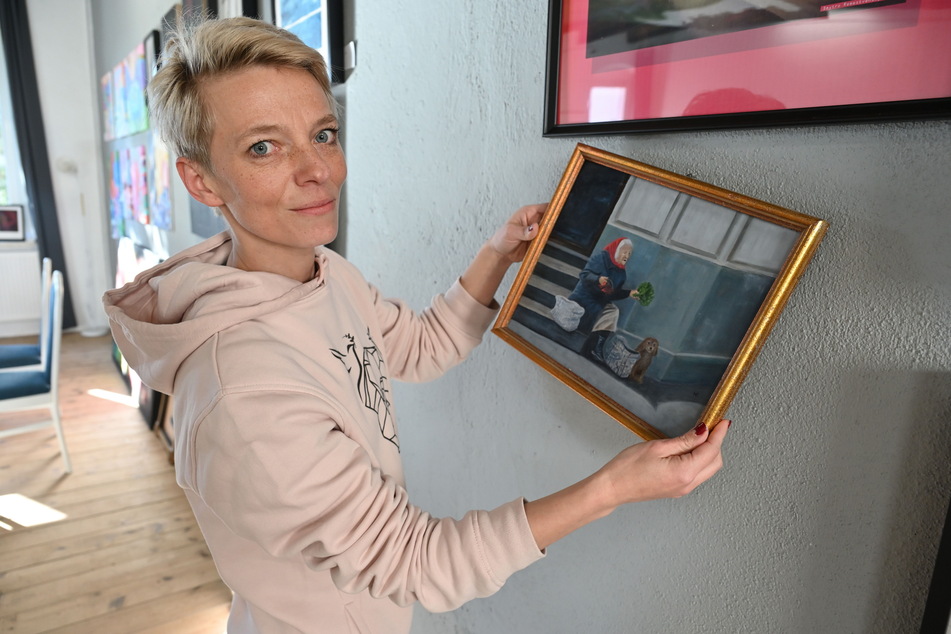 Denise Kendzia (40), Inhaberin von "Karls Kunsthaus", zeigt ein Bild der ukrainischen Künstlerin Hanna Remestvenska, das bei der Auktion verkauft wird.