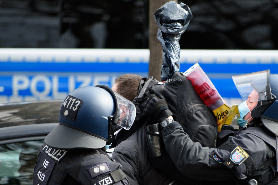 Ein Bild von der Demo in Kassel: Einsatzkräfte der Polizei halten einen Teilnehmer fest. (Archiv)