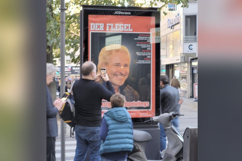 Neugierige Passanten machten am Samstag auch auf der Breite Straße Fotos der Satire-Plakate.