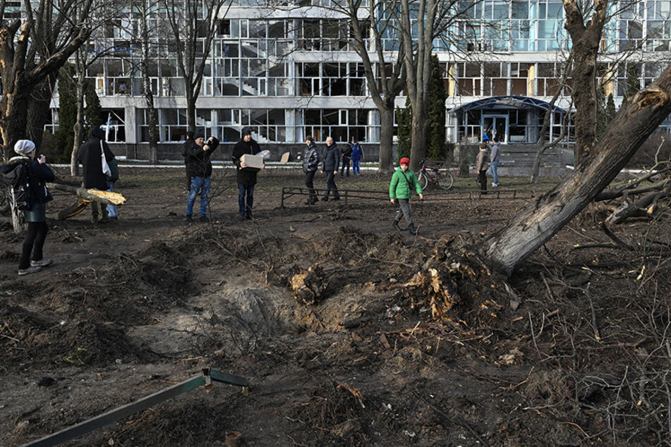 Bystanders look at the damage after a missile strike near an educational building in Kyiv.