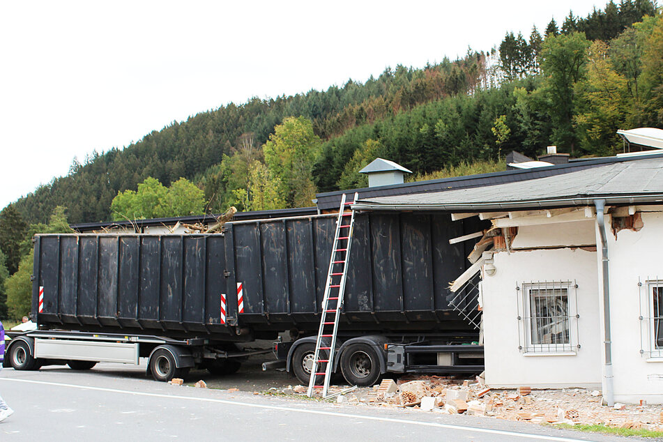 Ein Lastwagen mit Anhänger steht nach einem Unfall mit der Vorderseite im Gebäude eine Fabrik.
