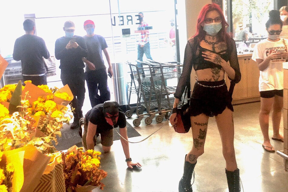 Unusual supermarket customer: A young dominatrix takes a man out shopping.