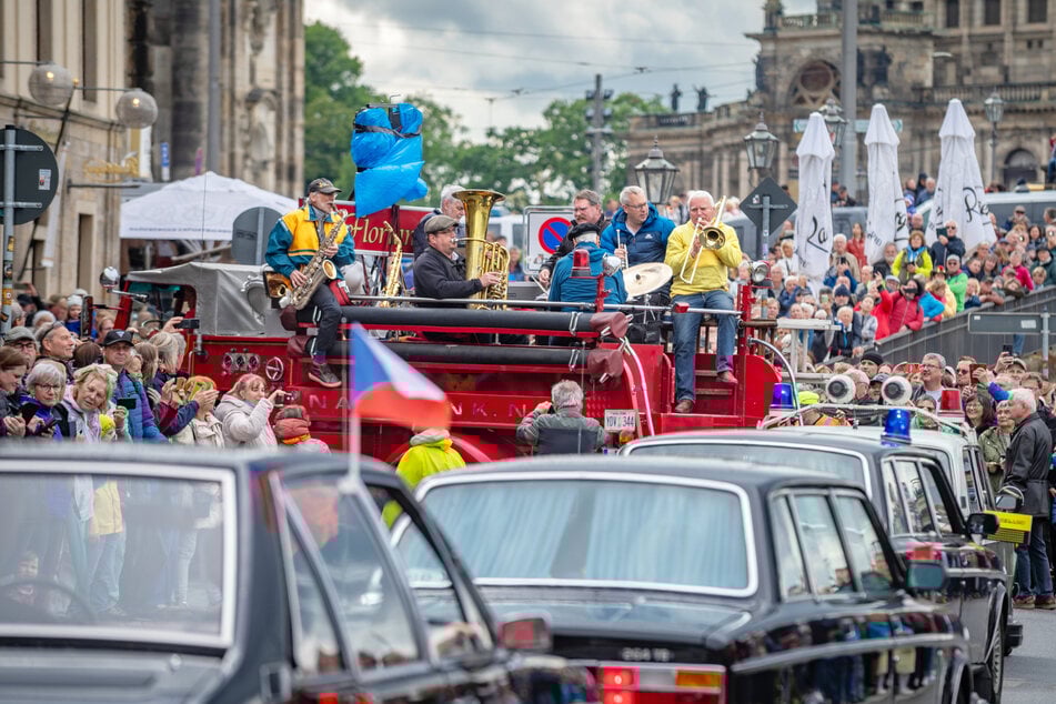 Etliche Oldtimer fahren bei der Parade entlang des Elbufers und werden dabei von spielenden Musikern begleitet.