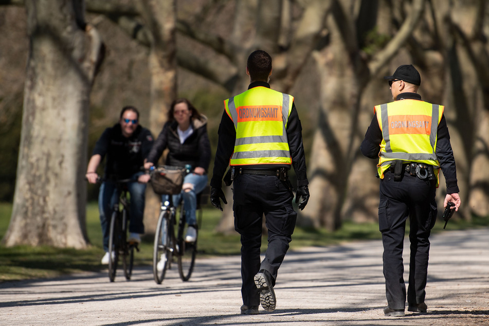 Mitarbeiter des Ordnungsamts kontrollieren in einem Park die Einhaltung der Schutzmaßnahmen gegen die Verbreitung des Coronavirus (Archivbild).