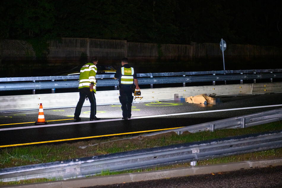 Polizisten im Einsatz. Die Leiche der Frau liegt auf der B75.