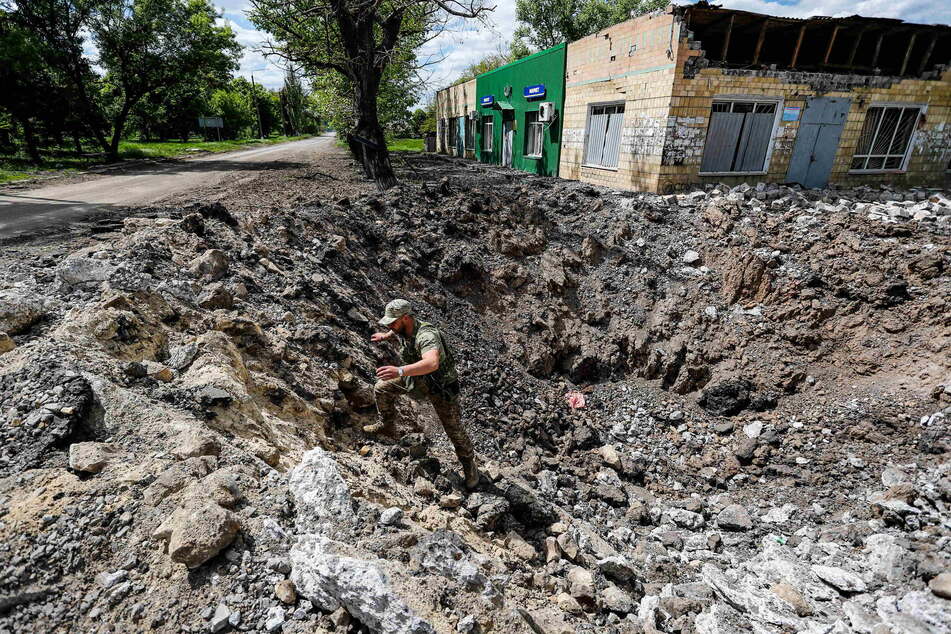Ein ukrainischer Soldat begutachtet ein riesiges Loch, das durch einen russischen Luftangriff am Rande der Donbass-Region entstanden sein soll.
