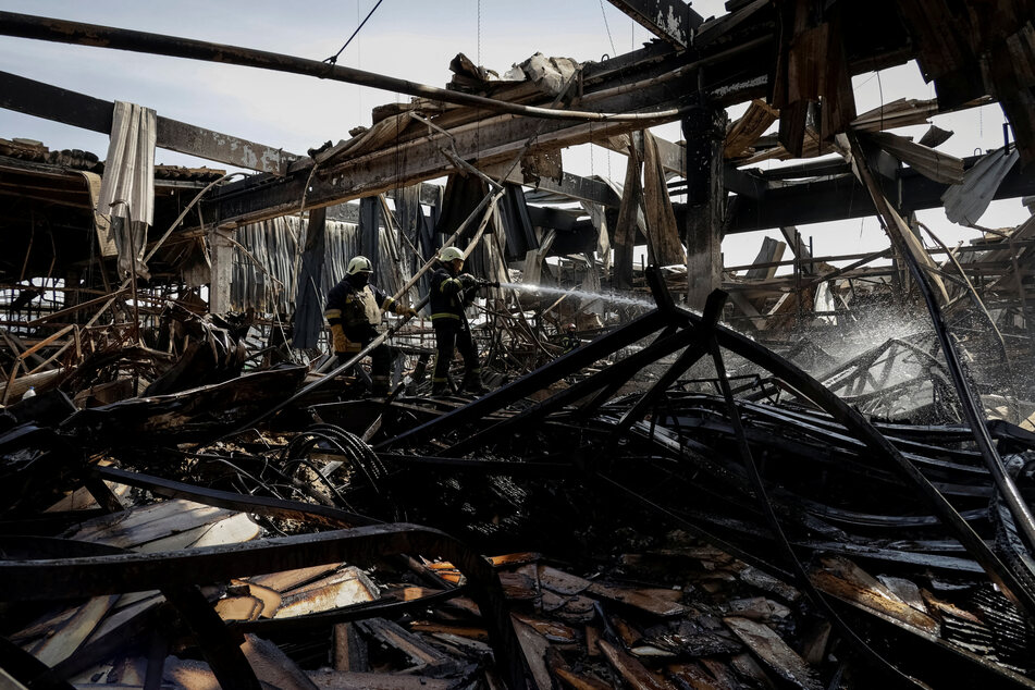 Firefighters work at a site of a household items shopping mall hit by a Russian airstrike in the Kharkiv region.