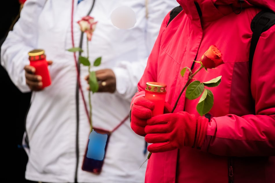 Menschen halten bei einer Mahnwache auf dem Platz vor der Oper in Magdeburg Kerzen und Blumen. Wenige Tage vor dem Fest ist es zu einem Anschlag auf den Weihnachtsmarkt der Landeshauptstadt Sachsen-Anhalts gekommen.