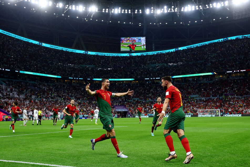 Cristiano Ronaldo (l.) and Bruno Fernandes celebrate after Portugal opens the scoring against Uruguay.