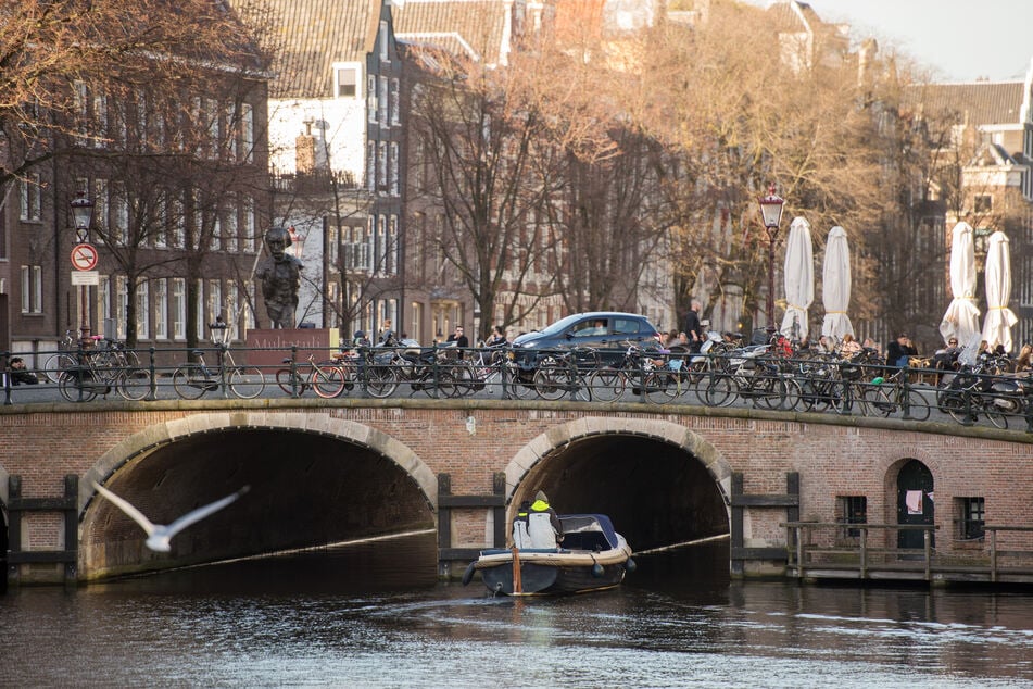 Ein Boot fährt auf einer Gracht unter einer Brücke in Amsterdam hindurch. Seit Anfang Juli stiegen die Infektionszahlen in der Niederlande um 500 Prozent innerhalb einer Woche.