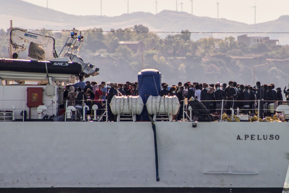 Migranten kommen an Bord von zwei Militärschiffen an.
