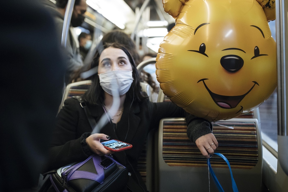 Paris: Eine Frau sitzt in der U-Bahn und hält einen Ballon von Pu der Bär. Um die Verbreitung des Coronavirus einzudämmen, sollen in Frankreich am 30. Oktober weitreichende Ausgangsbeschränkungen in Kraft treten.