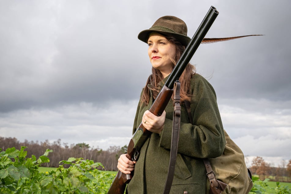 Eine junge Jägerin mit ihrem Jagdgewehr auf der Pirsch.