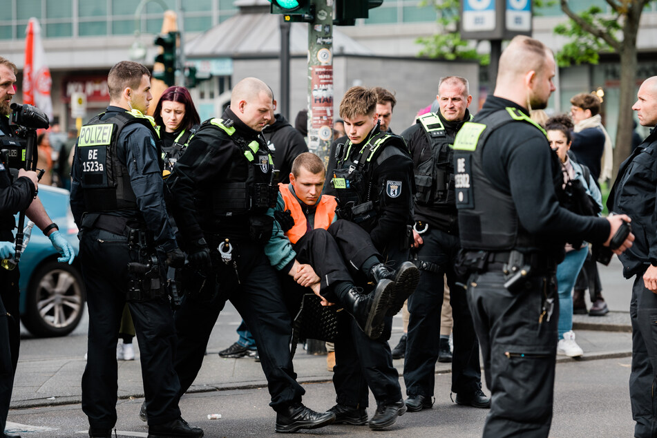 Die Polizisten tragen den Klimaaktivisten der "Letzten Generation" von der Straße.
