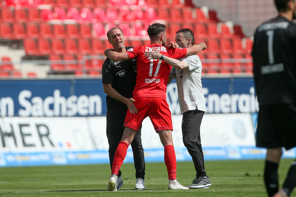 FSV-Coach Joe Enochs (l.) und Mannschaftsleiter Mario Kallisch (r.) umarmen Siegtorschütze Morris Schröter.