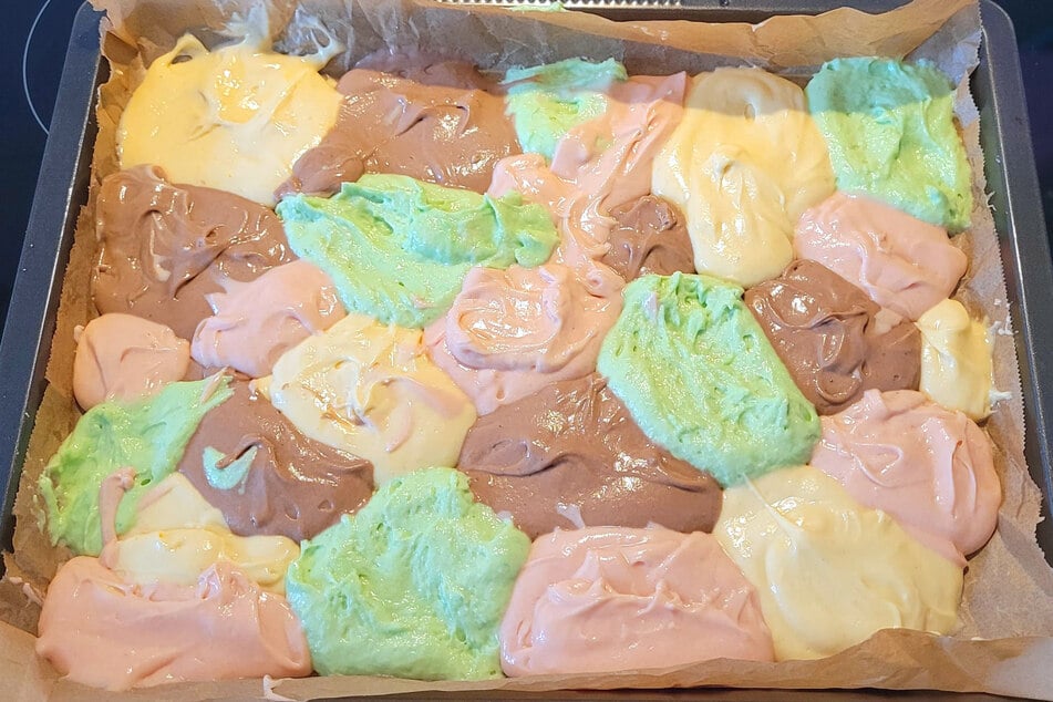 Den Teig für den Papageienkuchen so auf dem Backblech verteilen, dass sich die Farben nicht vermischen.