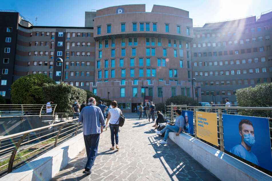 Personal, Besucher und Patienten gehen vor dem Krankenhaus San Raffaele, wo der ehemalige italienische Ministerpräsident Berlusconi ins Krankenhaus stationär aufgenommen wurde. Italiens ehemaliger Premierminister Berlusconi ist nach Angaben seiner Partei wegen seiner Corona-Infektion mit Symptomen ins Krankenhaus gekommen.