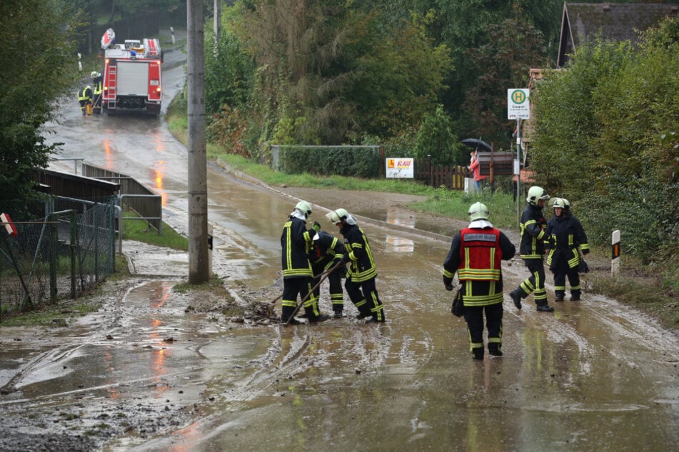 Feuerwehrleute befreien die Straße vom Schlamm.