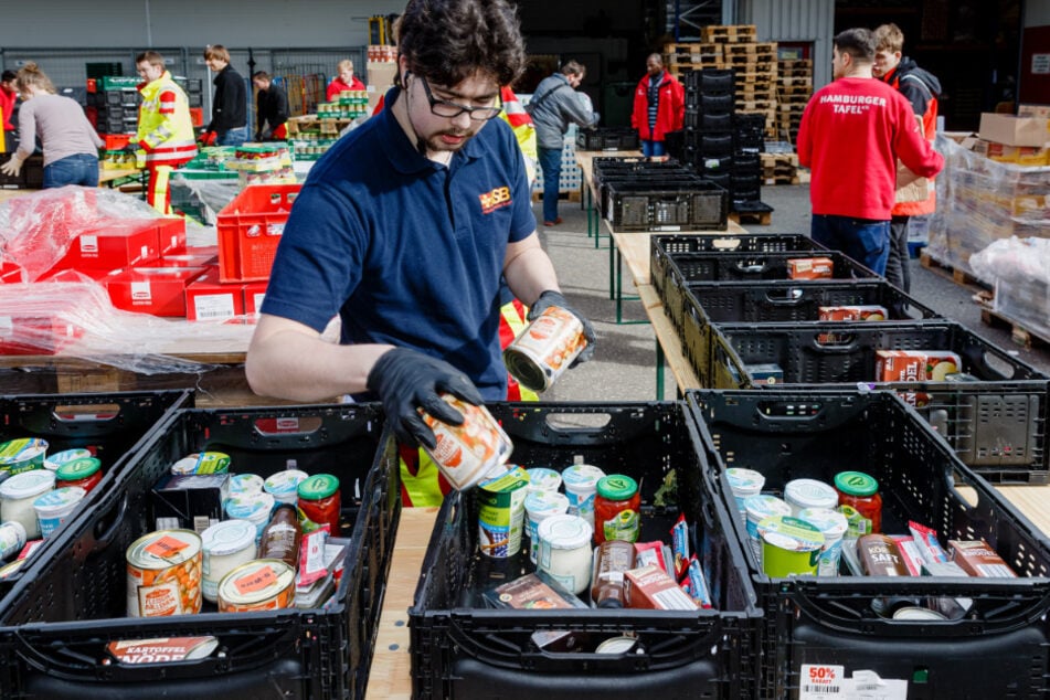 Ehrenamtliche Helfer der Hamburger Tafel und des Arbeiter-Samariter-Bunds packen im Zentraldepot Kisten mit Lebensmitteln.