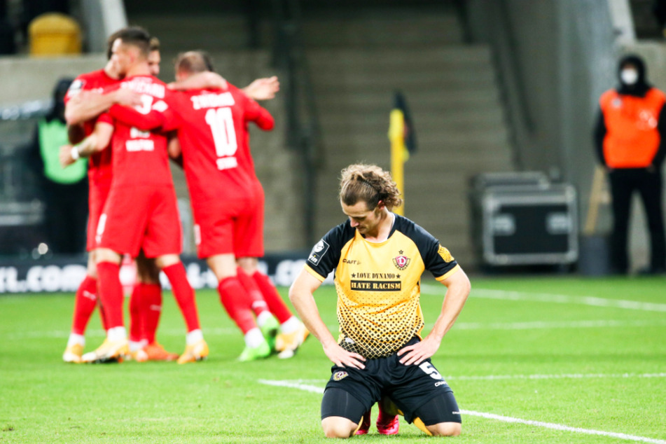 Während Dynamo-Kämpfer Yannick Stark (r.) auf dem Boden kniet, bejubeln die Spieler des FSV Zwickau ihr Tor.