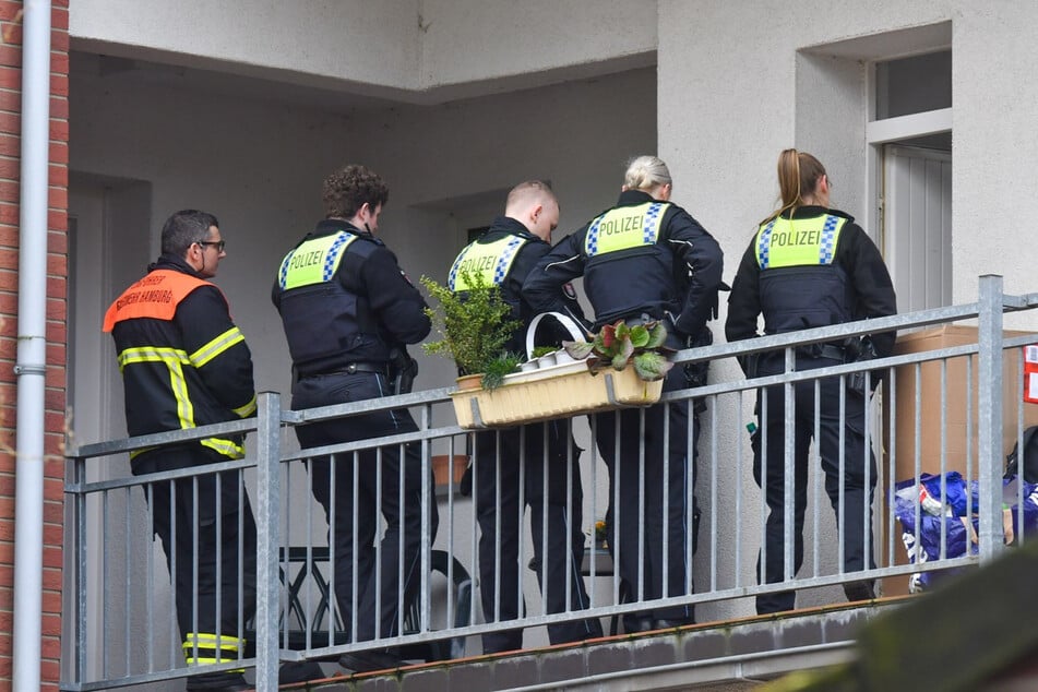 Einsatzkräfte von Polizei und Rettungsdienst stehen vor der Wohnung in Hamburg-Billstedt.