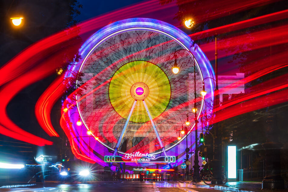 Ein Riesenrad leuchtet am späten Abend auf dem Münchner Königsplatz vor der Kulisse der Propyläen, das dort für den "Sommer in der Stadt" aufgebaut ist.