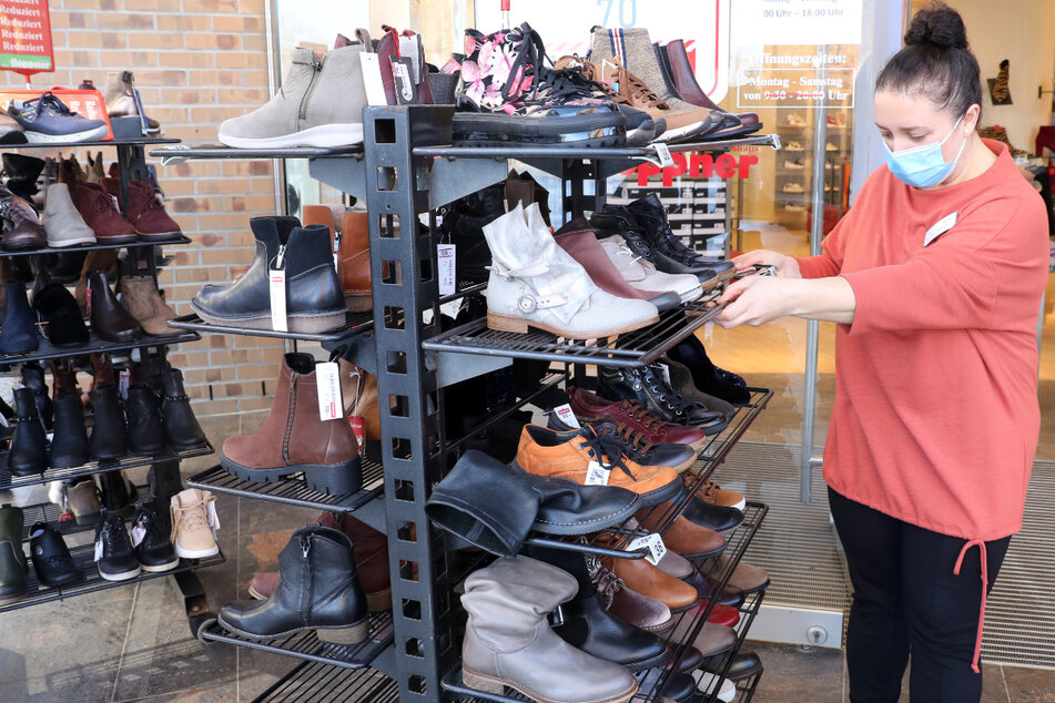 Für die Wiedereröffnung des Einzelhandels schiebt eine Verkäuferin Rollwagen mit Schuhen ins Freie.