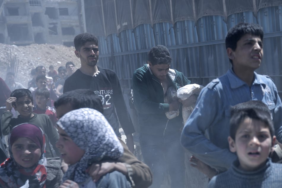 Syrien, Duma: Ein Jugendlicher steckt Brot in seine Tasche, nachdem Mitarbeiter der syrischen Regierung Nahrungsmittel an die Bewohner von Duma verteilten. (Archivbild)
