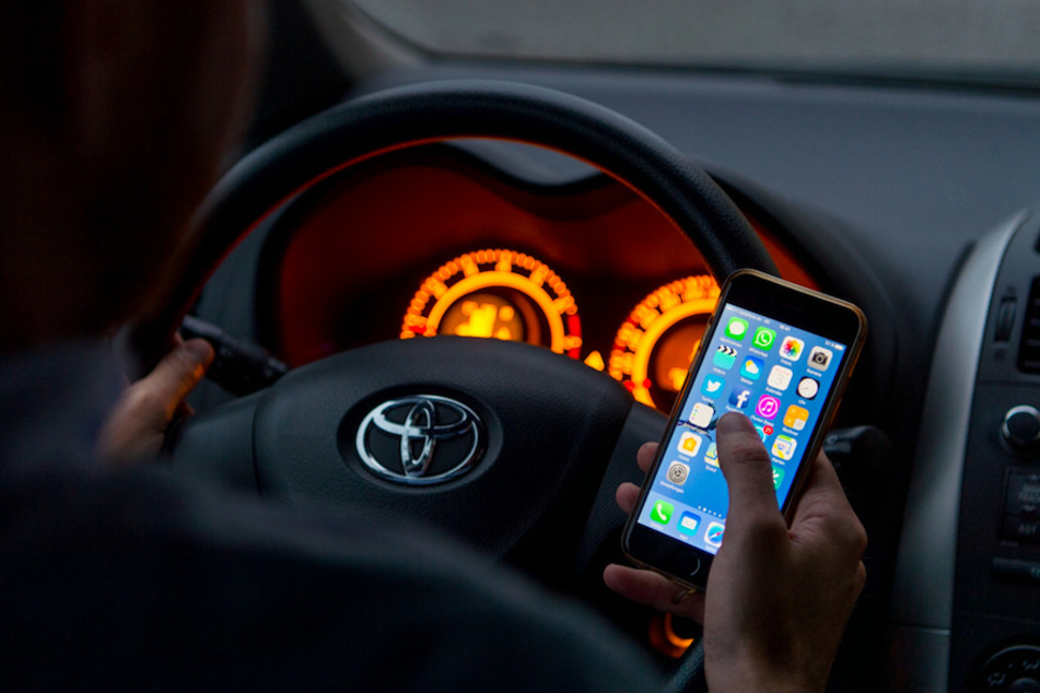 Wer am Steuer mit dem Smartphone hantiert muss mit Bußgeld, Punkt und Fahrverbot rechnen.