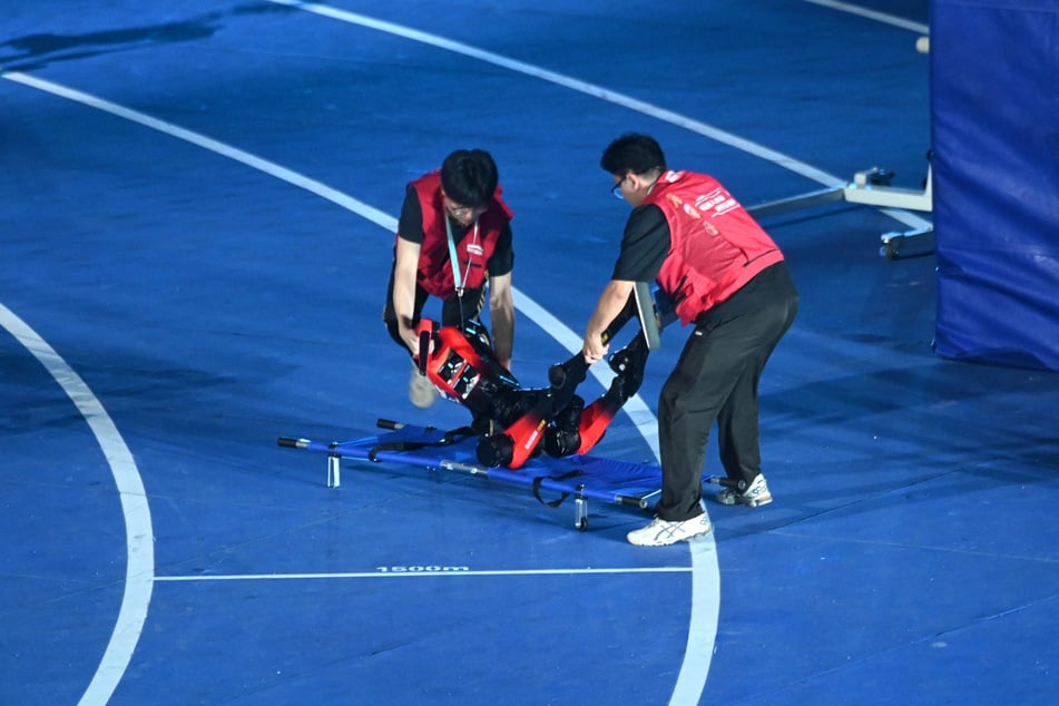Der humanoide Roboter "Blitz" des chinesischen Handy-Herstellers Honor wird nach einem 100-Metersprint auf eine Trage gelegt.