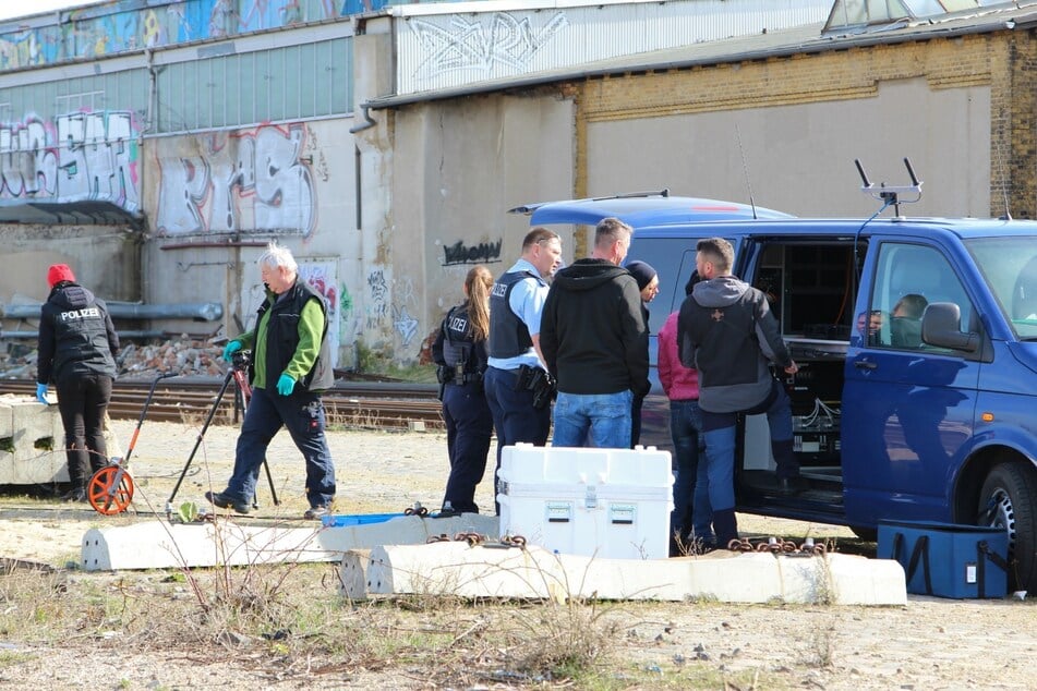 Besprechung am Einsatzwagen der Kriminalisten - im Hintergrund ist das Bahngebäude zu sehen, vor dem die tote Frau lag.