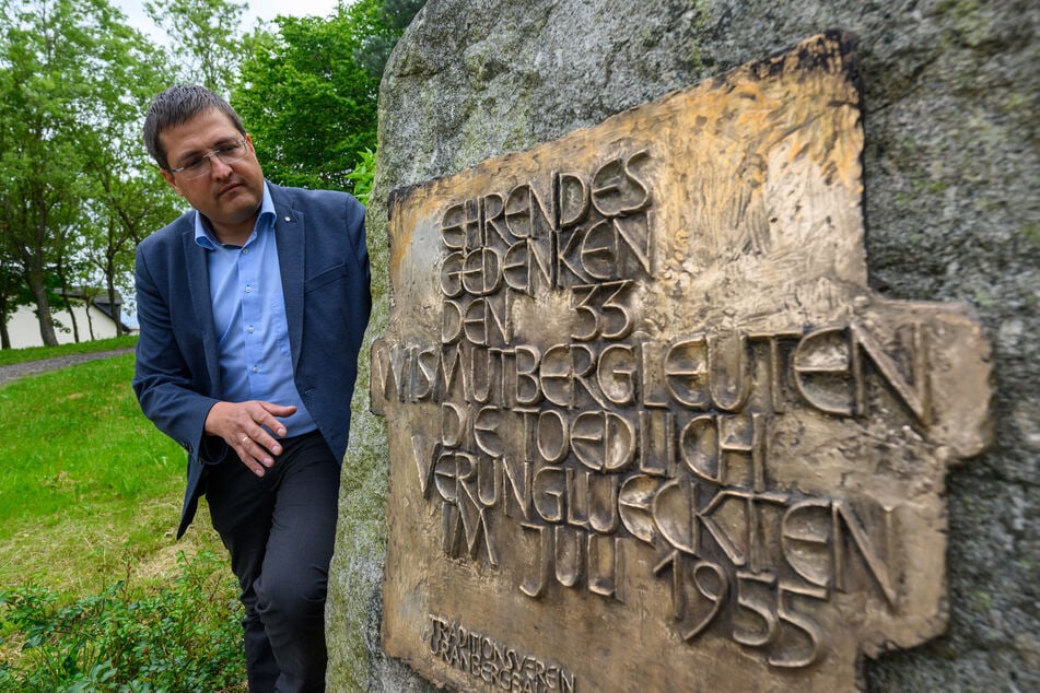 Andy Tauber, Bereichsleiter der Wismut GmbH, steht neben einer Gedenktafel.