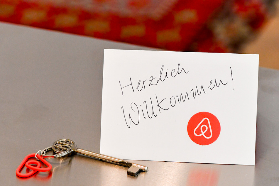 Ein Schlüssel mit einem Airbnb-Anhäger und eine Herzlich-Willkommen-Karte liegen in der Wohnung eines Airbnb-Gastgebers für den Gast bereit. (Symbolbild)
