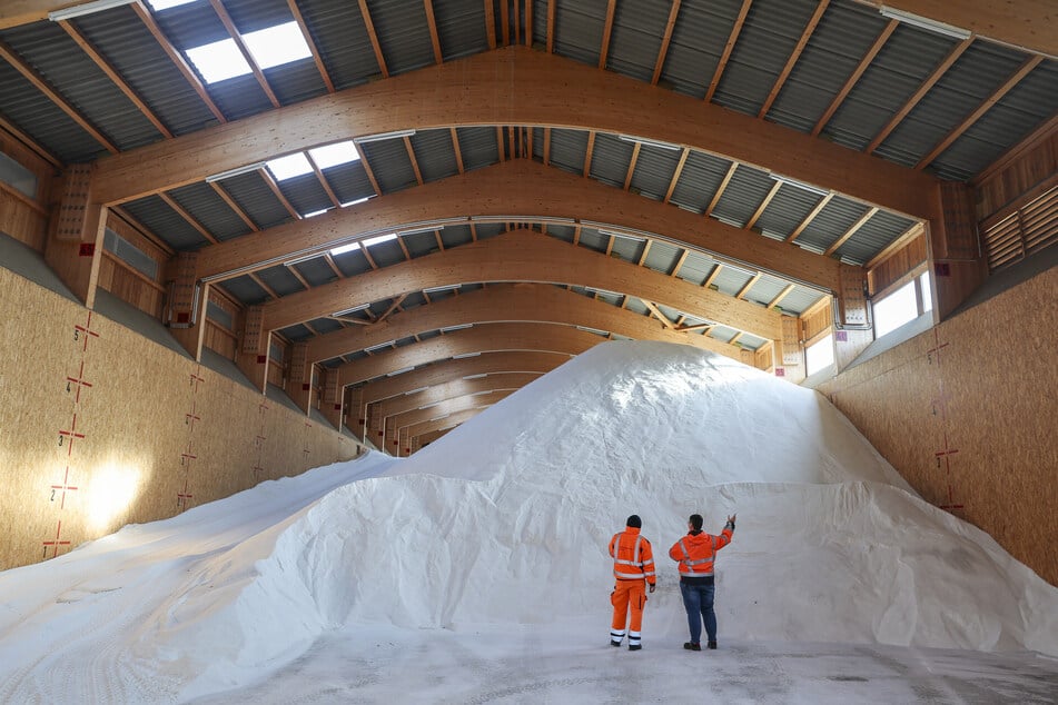 Zwei Mitarbeiter stehen vor 4400 Tonnen Streusalz in der Lagerhalle der Stadtreinigung Leipzig.