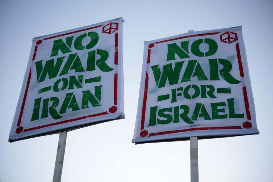 Anti-war demonstrators hold signs as they gather near the White House to protest the US-Israeli war on Iran on April 7, 2026.