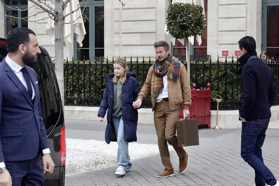 Zum camelfarbenen Herbstlook wählt Starkicker David Beckham einen karierten Schal und einen schicken Louis Vuitton Aktenkoffer.